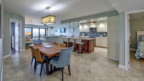 Une cuisine spacieuse avec un coin repas, un grand îlot central et une vue sur l’extérieur.