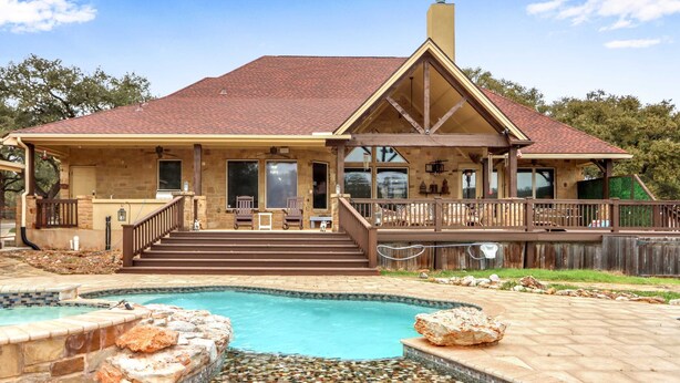 Una casa con piscina, terraza y patio de piedra.