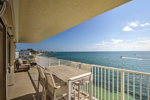 A balcony with a view of the ocean, a table, and chairs. - Premier Oceanfront Top Floor Condo With Wraparound Balcony & Windows (Key Colony Beach)