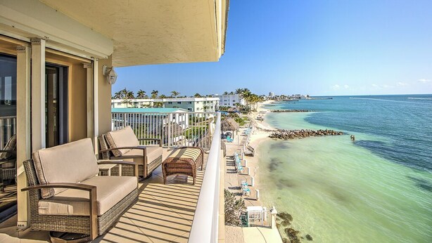 A balcony with wicker furniture and a view of the ocean. - Premier Oceanfront Top Floor Condo With Wraparound Balcony & Windows (Key Colony Beach)