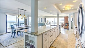 A spacious kitchen with a large island, modern appliances, and a view to the outside. - Premier Oceanfront Top Floor Condo With Wraparound Balcony & Windows (Key Colony Beach)