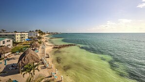 A beachfront hotel with thatched umbrellas, sun loungers, and a clear view of the ocean. - Premier Oceanfront Top Floor Condo With Wraparound Balcony & Windows (Key Colony Beach)