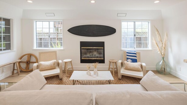 A spacious living room with a large window, a fireplace, and a modern art piece.