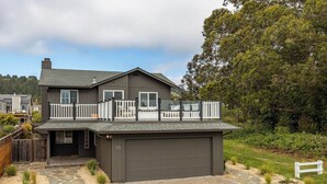 A two-story house with a garage, a balcony, and a stone pathway leading to the entrance.
