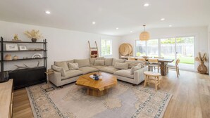 Amplia sala de estar con un sofá en forma de L, una mesa de centro de madera y una zona de comedor con mesa y sillas.
