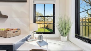 A kitchen with a large window, a wicker basket, a lamp, and a potted plant. - King Beds in Safe Area • Game Room • Patio & Grill (Wichita)