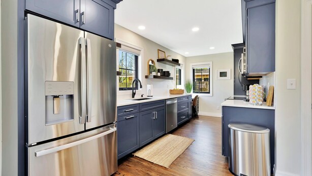 A modern kitchen with stainless steel appliances, dark cabinetry, and a wooden floor. - King Beds in Safe Area • Game Room • Patio & Grill (Wichita)
