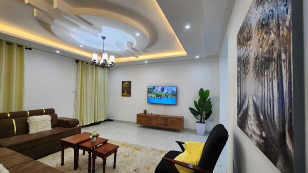 A modern living room with a sofa, coffee table, TV, and artwork on the wall.