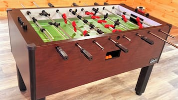 A foosball table with a wooden frame and a green playing surface.