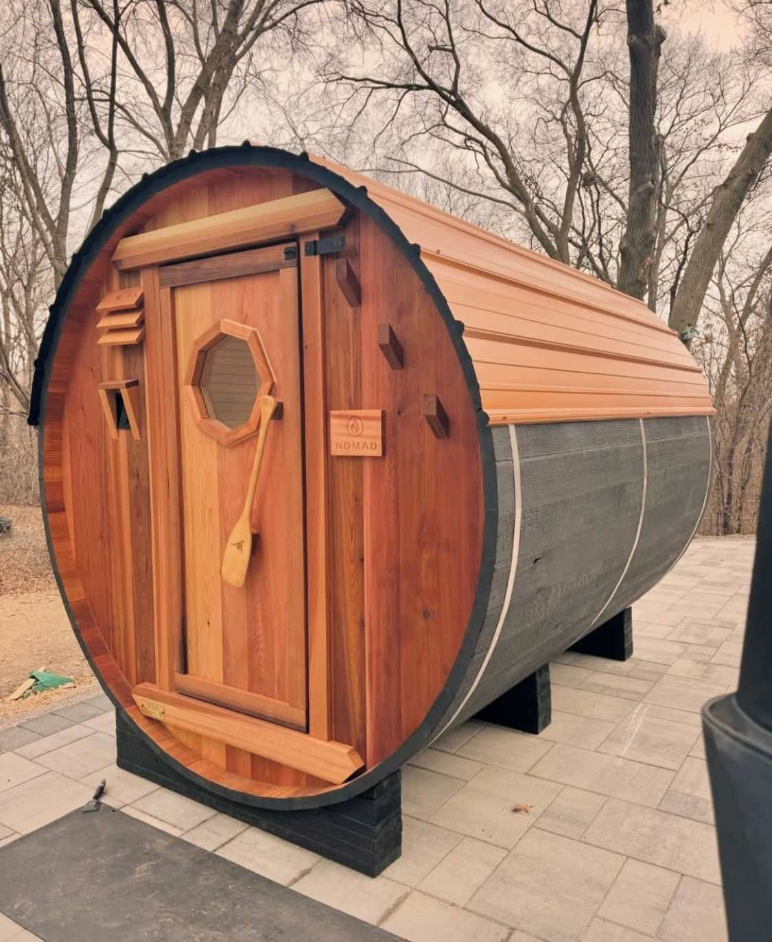 Una struttura a forma di botte in legno con una porta e un cartello con la scritta 'NOMAD'.