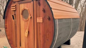 Una struttura a forma di botte in legno con una porta e un cartello con la scritta 'NOMAD'.