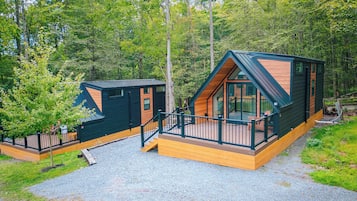 Een chalet met een terras en een overdekte veranda, omringd door bomen.