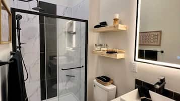 A modern bathroom with a glass-enclosed shower, a white toilet, a sink with a mirror, and a towel rack.
