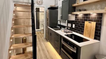 A modern kitchen with a central island, built-in appliances, and a wooden staircase.