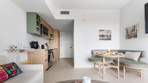 A modern living room with a sofa, a coffee table, and a dining area with a table and chairs.