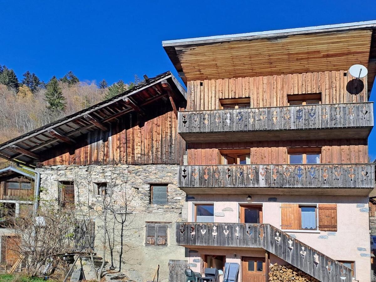 Un chalet in legno su più piani, con balconi, pareti in pietra e un'antenna parabolica.