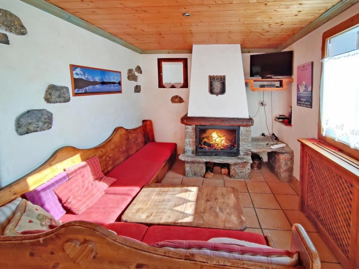 A cozy living room with a stone fireplace, wooden furniture, and a stone wall.