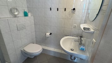 A modern bathroom with a toilet, sink, and shower.