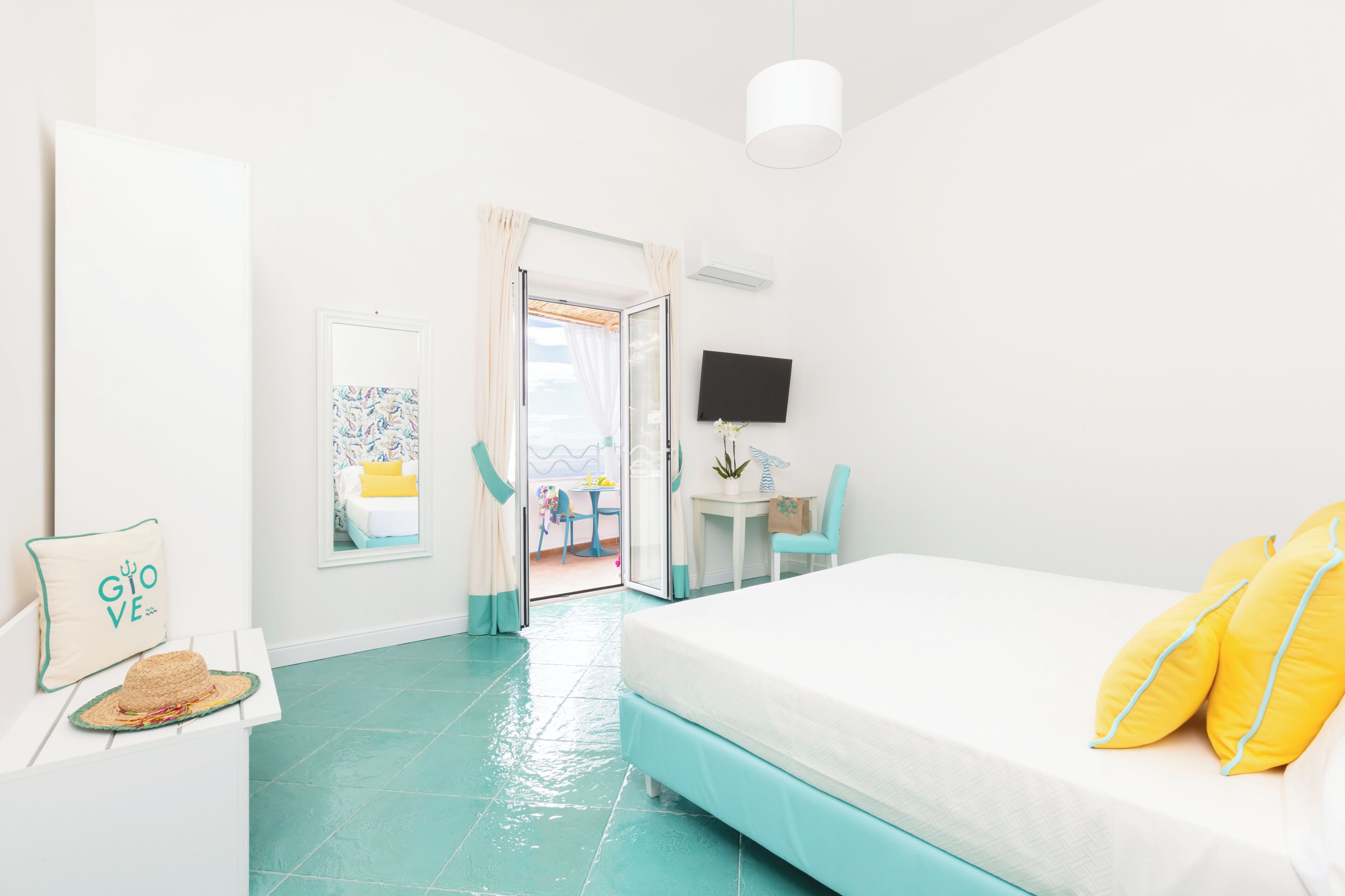 A bright room with a bed, a desk, and a TV.