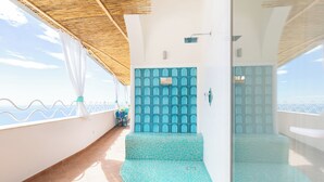 Un balcone con pavimento piastrellato, un'area salotto e vista sull'oceano.