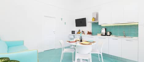 A modern kitchen with white cabinets, a dining table with chairs, and a teal floor.