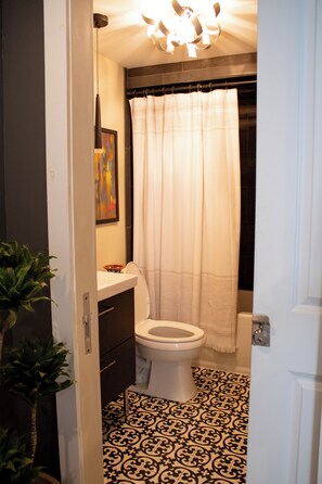 Une salle de bain avec des toilettes, un lavabo, un rideau de douche et un carrelage décoré.