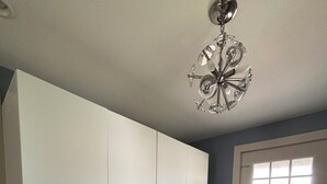 Una habitación con un amplio armario blanco, una mesa de comedor de madera con superficie de vidrio y una araña.