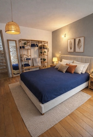 Un dormitorio con una cama, un armario de madera, una mesita de noche, una lámpara y hojas enmarcadas en la pared.