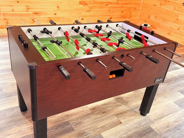 A foosball table with a wooden frame and a green playing surface.