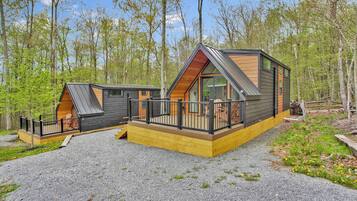 A cabin with a sloped roof, large windows, and a deck.
