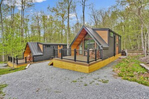 A cabin with a sloped roof, large windows, and a deck.