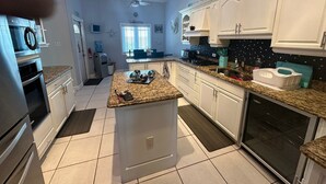 A modern kitchen with white cabinets, granite countertops, and stainless steel appliances.