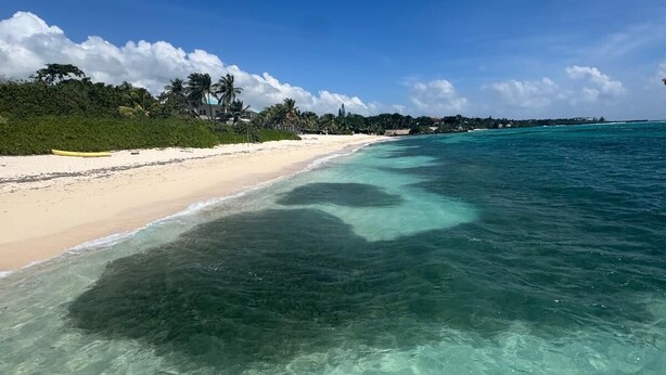 A clear view of a beach with a wooden deck in the foreground.