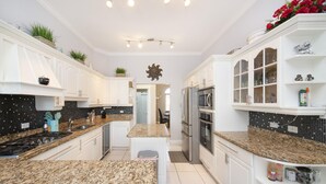 A modern kitchen with white cabinetry, granite countertops, and a central island.