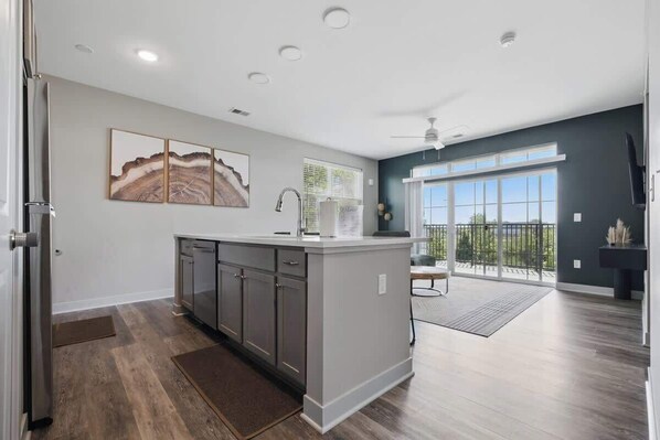 A modern kitchen with grey cabinets, a central island, and a large window.