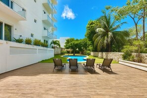 A modern building with a swimming pool, surrounded by palm trees and a well-maintained lawn.