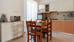 Eine kompakte Küche mit Esstisch, Stühlen, einer Mikrowelle, einem Backofen und einem Spülbecken.