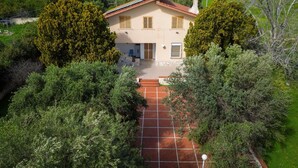 Ein zweistöckiges Haus mit gefliestem Patio, umgeben von dichtem Grün und Bäumen.