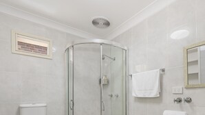 Un baño moderno con ducha de vidrio, inodoro y tocador con espejo.