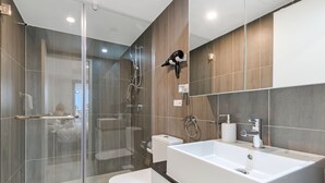 Un bagno moderno con doccia vetro, lavandino bianco e specchio.