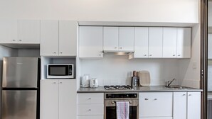 A modern kitchen with stainless steel appliances, white cabinets, and a built-in oven. - Kozyguru | Chippendale | Kozy Clean 1Bed Apt (Chippendale)