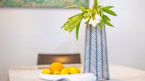 A table with a vase of flowers, a bowl of lemons, and an open magazine. - Kozyguru | Forestville | Charming 3Br House (Forestville)