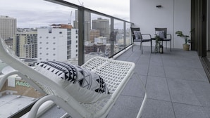 Un balcon avec deux fauteuils de jardin blancs, une petite table avec des chaises et une plante en pot.