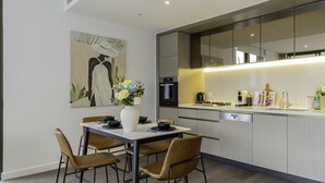 Une cuisine moderne avec un coin repas, comprenant une table blanche, des chaises marron et un vase avec des fleurs.