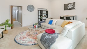 Een moderne woonkamer met een witte bank, een ronde salontafel en een kamerkleed met een patroon.