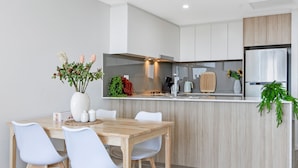 Une cuisine moderne avec une table et des chaises en bois, un four encastré et un réfrigérateur.