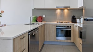 Une cuisine moderne avec des meubles en bois, des appareils électroménagers en acier inoxydable et un lave-vaisselle intégré.