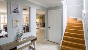 A hallway with a wooden bench, a door, and a staircase. - Kozyguru | Prestons Dream Holiday House + Parking (Prestons)