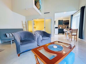 A modern living room with a grey sofa, a wooden coffee table, and a dining area with a table and chairs. - Kozyguru | Summer Hill | 1 Bed Townhouse (Summer Hill)