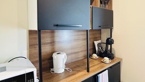 A kitchenette with a microwave, kettle, and coffee maker on a wooden countertop. - Kozyguru | Summer Hill | 1 Bed Townhouse (Summer Hill)